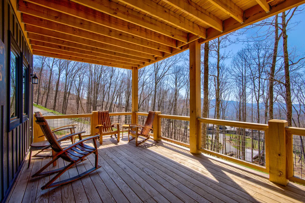 This image highlights a tranquil wooden deck surrounded by trees, with cozy rocking chairs providing a perfect spot to relax and enjoy the fresh mountain air. The deck is directly connected to nature, making it an ideal setting for guests and their pets to unwind after a walk or meal outdoors.