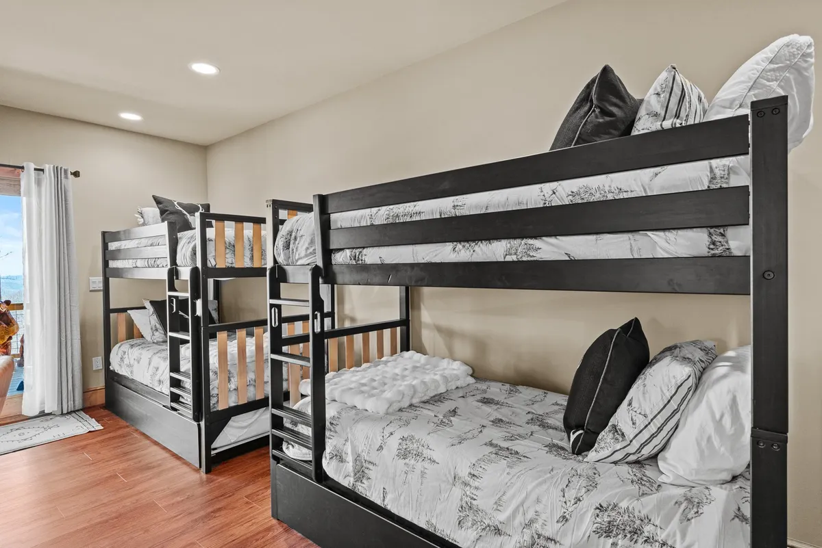 A cheerful, playful bunkroom interior with cozy bunk beds, soft bedding, and natural light streaming in from a window. The space feels welcoming and perfect for kids' sleepovers, story time, and movie nights, tying in the family-centric aspect of the home.